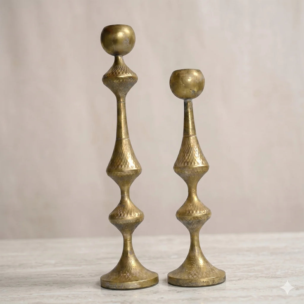 Antique gold hammered metal candle holders set on marble surface