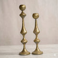 Antique gold hammered metal candle holders set on marble surface