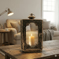 Rustic gold metal and glass lantern with candle on wooden table in cosy living room