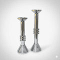 Two modern chrome sculptural candle holders on white background