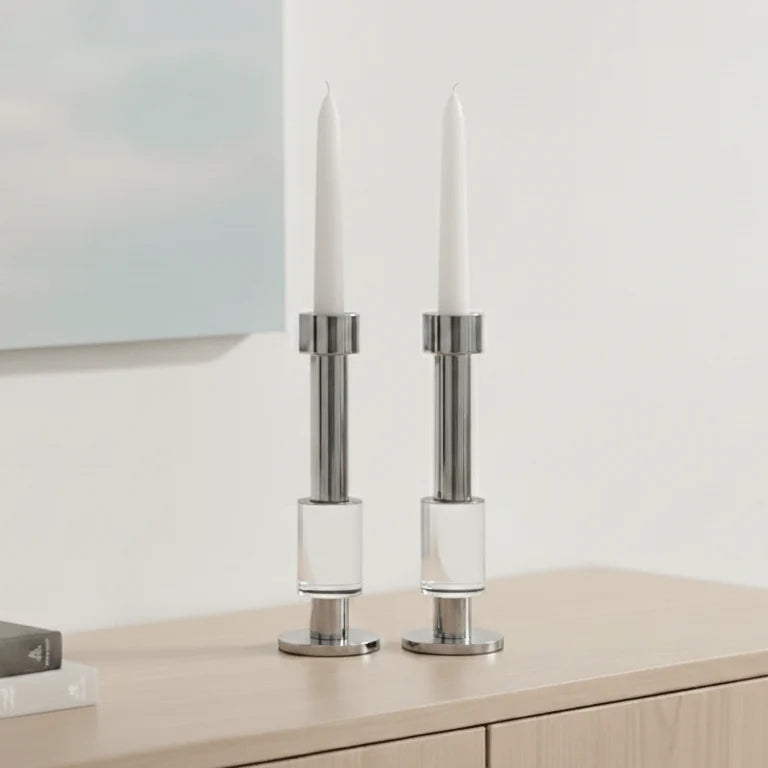 Crystal and chrome candle holders with white candles on wooden sideboard