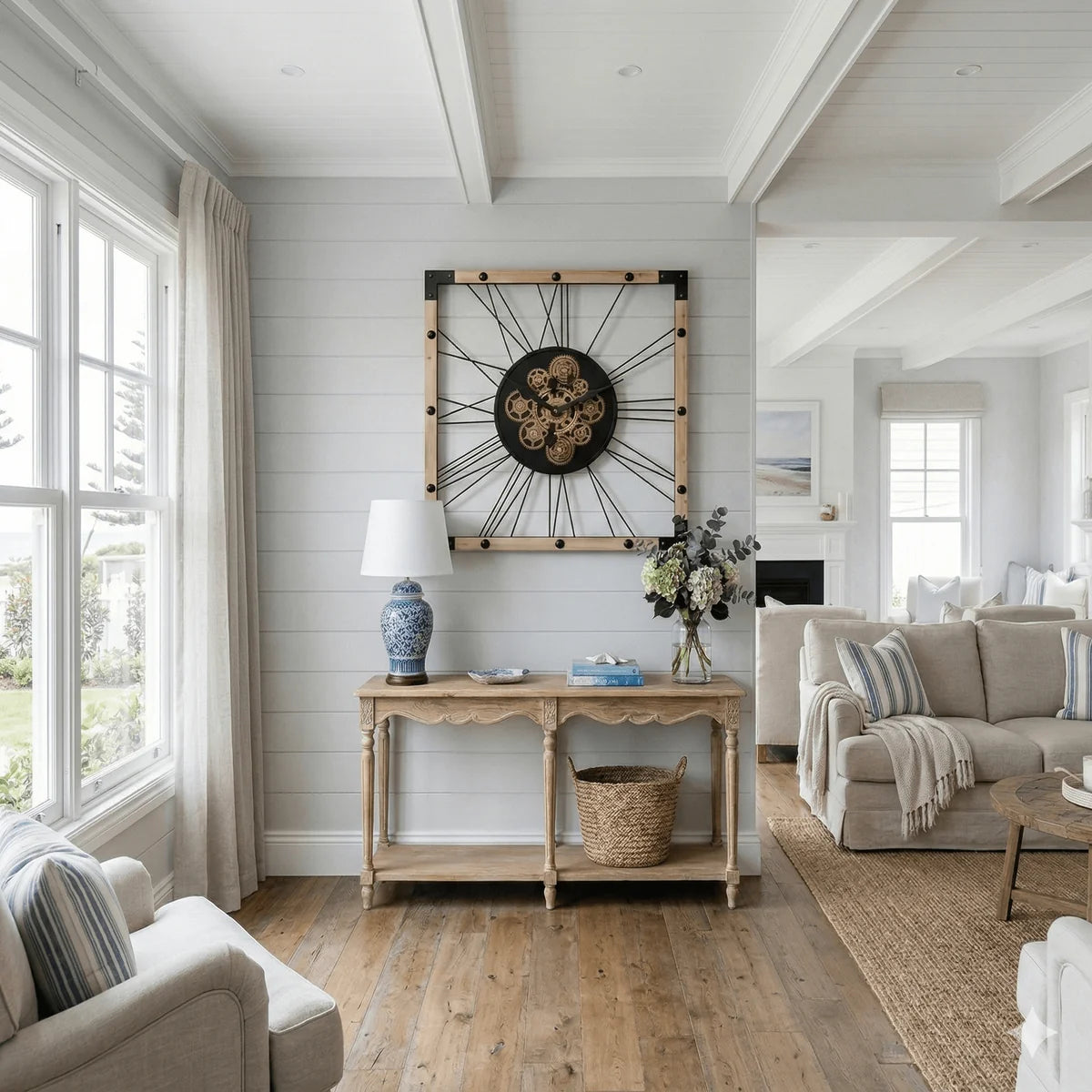Large industrial wall clock hanging above a hallway table in a modern living room
