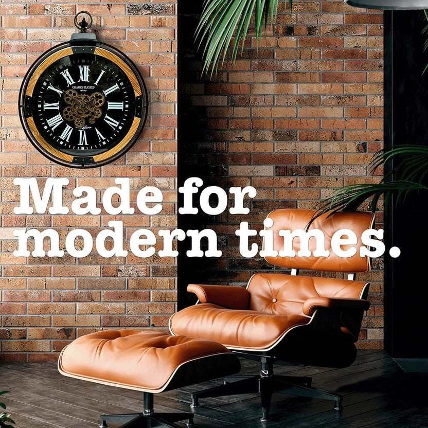 Industrial wall clock mounted on a brick wall with modern lounge chair below and caption 'Made for modern times'
