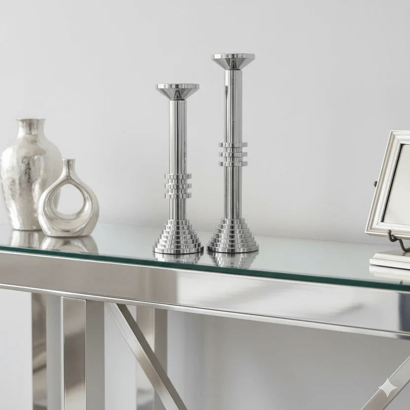 Sculptural chrome candle holders styled on console table with decor